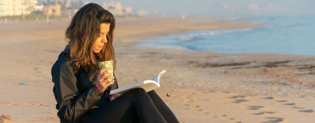 Woman reading on beach - Why Recovery Isn’t Linear